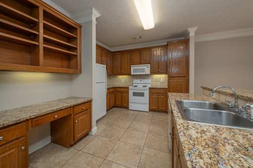 A kitchen with a granite counter top and wooden cabinets.