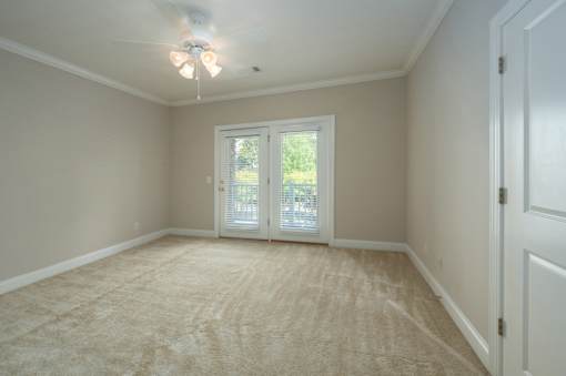 A room with a carpeted floor and a ceiling fan.
