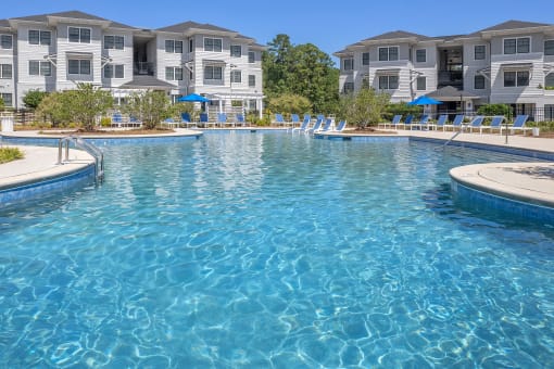 a large swimming pool with apartments in the background