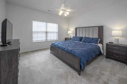 A bedroom with a bed, dresser, and television.