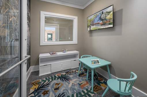 A room with a desk, chair, and a painting of a train on the wall.