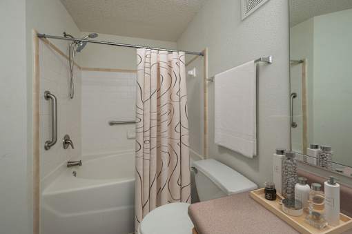 A bathroom with a white tub and a shower curtain with a pattern.
