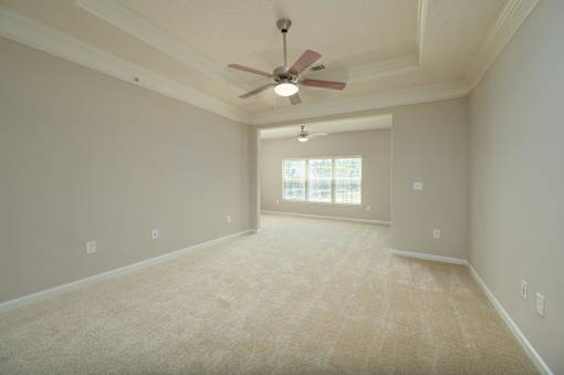 A room with a ceiling fan and carpeted floor.