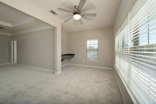 A room with a ceiling fan and a window with blinds.