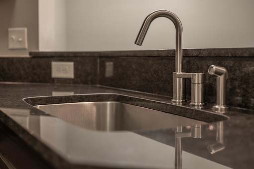 A modern sink with a chrome faucet and a dark granite countertop.