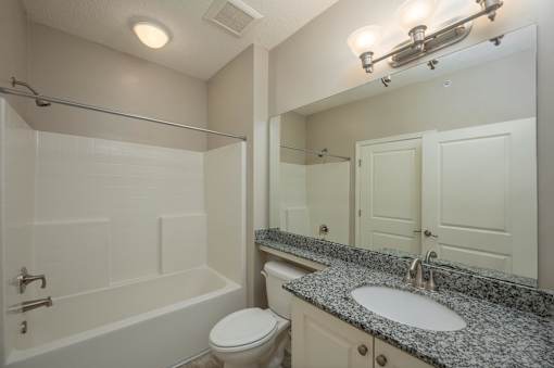 A bathroom with a granite countertop and white fixtures.