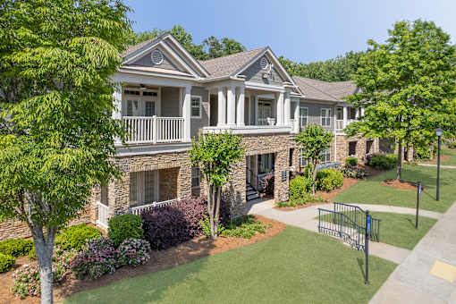 A house with a white porch and a green lawn.