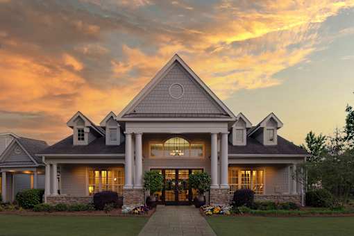 A large house with a front porch and a stone wall.