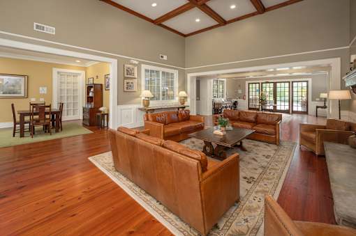 A large brown leather couch sits in the middle of a spacious living room.