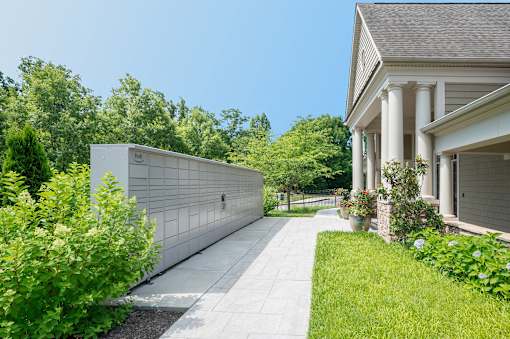 A white building with a long hallway is surrounded by greenery.