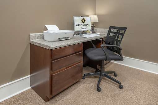 A brown desk with a printer and a sign that says "Greystone Homes".