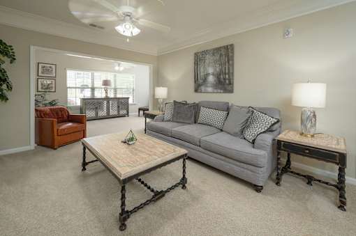 A living room with a grey couch, a wooden coffee table, and a ceiling fan.
