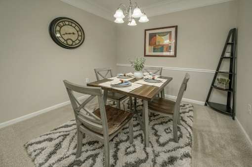 A dining room with a table set for two and a clock on the wall.