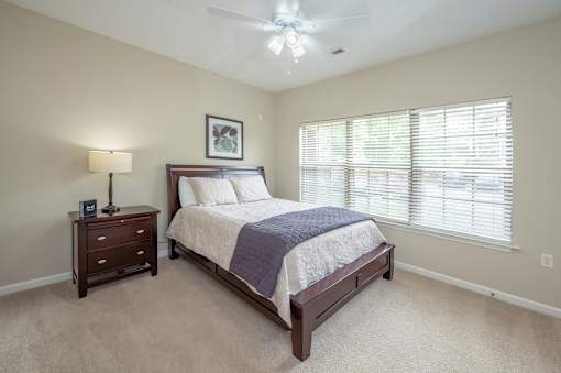A bedroom with a bed, nightstand, and window.