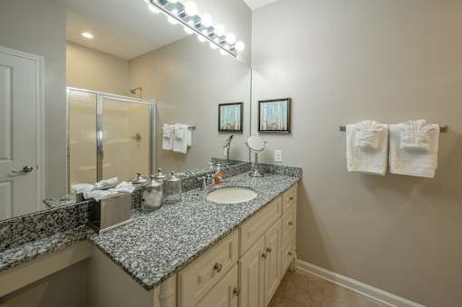 A bathroom with a granite counter top and a mirror.