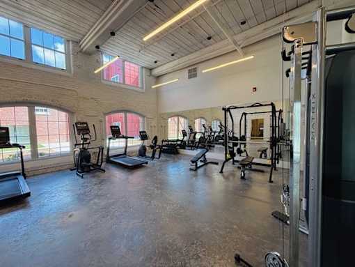 A gym with a variety of equipment including treadmills, weights, and exercise machines.