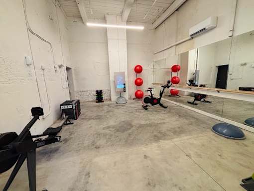 A gym with a mirror, weights, and exercise equipment.