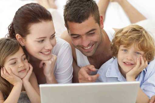 A family of four is looking at a laptop together.
