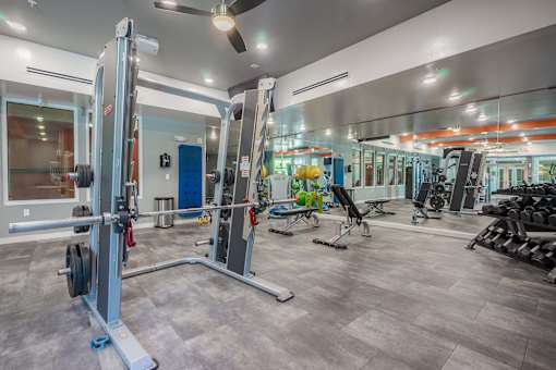 A gym with a variety of equipment including a squat rack and weights.