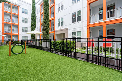 A playground area with a green slide and a black fence.