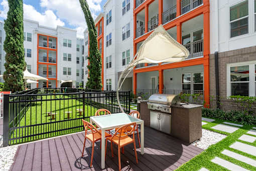 A patio with a table and chairs and a grill.