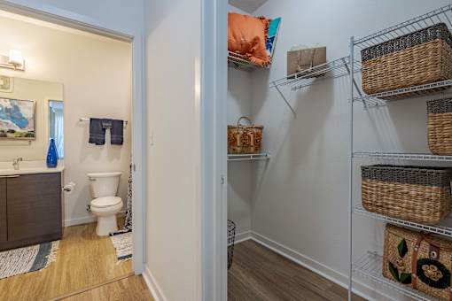 A bathroom with a toilet and a shelf with baskets on it.