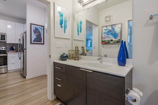 A bathroom with a sink, mirror, and two vases.