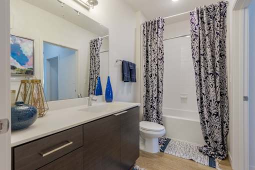 A bathroom with a toilet, sink, and shower curtain.