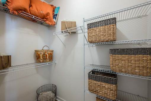 A white shelving unit with baskets and bags on it.