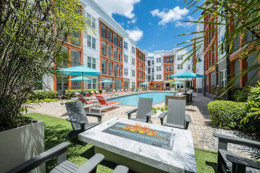 A pool surrounded by chairs and umbrellas in a courtyard.