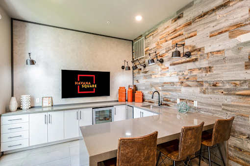 A kitchen with a wooden wall and a TV displaying the text "HYANNA SQUARE".