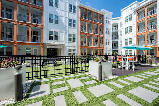 A white and orange building with a black fence and a green lawn in front.