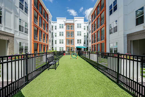 A grassy area in front of a building with a bench and a playground.