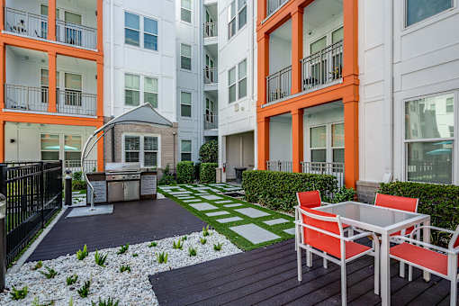 A patio with a table and chairs is surrounded by apartment buildings.