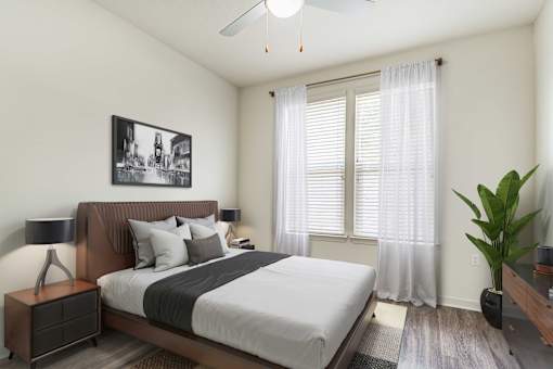 A bedroom with a bed, nightstand, and a plant.