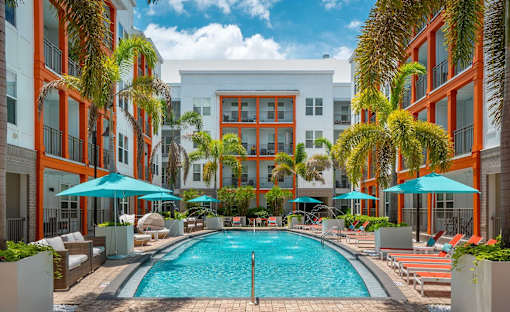 A pool surrounded by palm trees and lounge chairs.