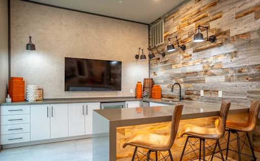 A kitchen with a stone wall and a countertop with chairs.