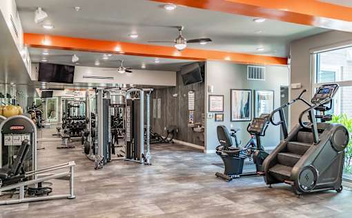 A gym with a variety of equipment including treadmills, weights, and exercise machines.