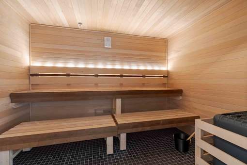 A wooden sauna with benches and lights on the wall.