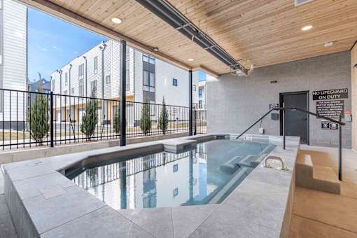 Bozeman, MT Townhomes with In-Unit Washer and Dryer - Highmark Bozeman - Covered Spa With Clear Water, Handrail Entry, Wood Ceiling, Black Fencing, And Modern Townhome Buildings Nearby.