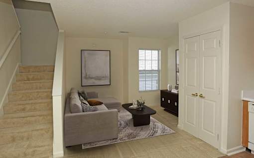 A living room with a couch, a coffee table, and a painting on the wall.