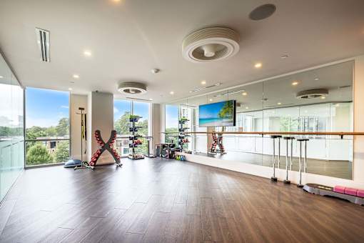 A spacious room with a large screen on the wall and a balcony with a railing.