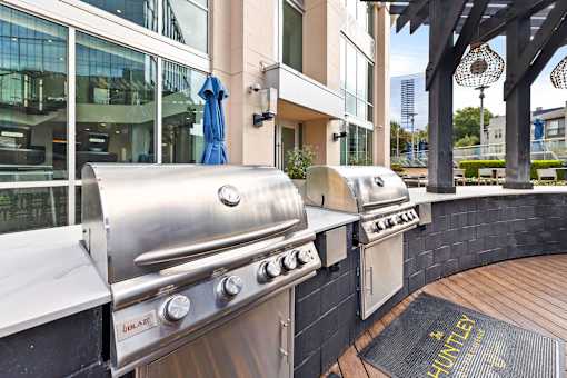 A stainless steel outdoor grill is on a wooden deck.