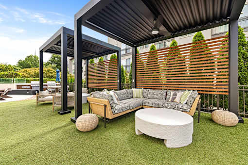 A modern outdoor seating area with a wooden bench and a white cushion.