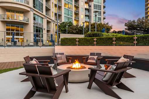 Buckhead, GA, Luxury Apartments With In-Unit Washer and Dryer - The Huntley - Outdoor Patio With Fire Pit, Cushioned Adirondack Chairs, and Evening Building Views.