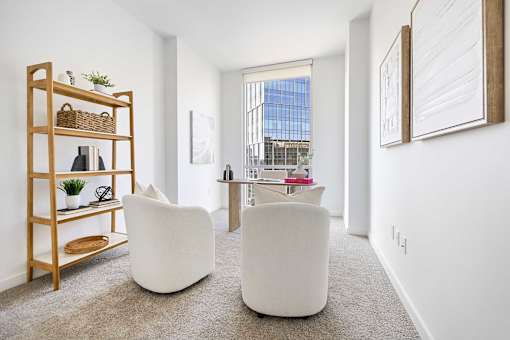 A white chair sits in a room with a wooden shelf and a window.