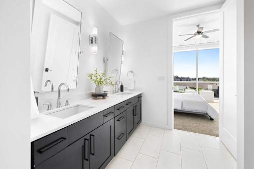 A bathroom with a black vanity and a white ceiling fan.