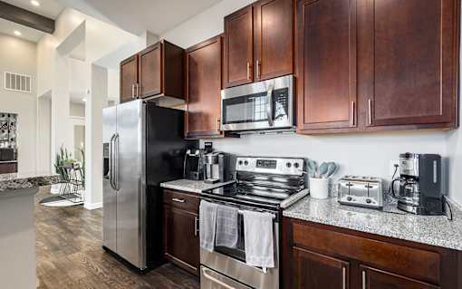 A modern kitchen with dark wood cabinets and stainless steel appliances.