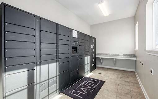 A room with a row of black lockers on the wall and a bench.