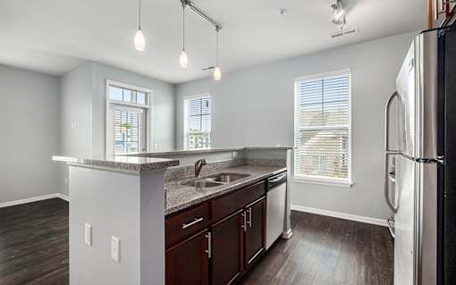A kitchen with a refrigerator, sink, and cabinets.